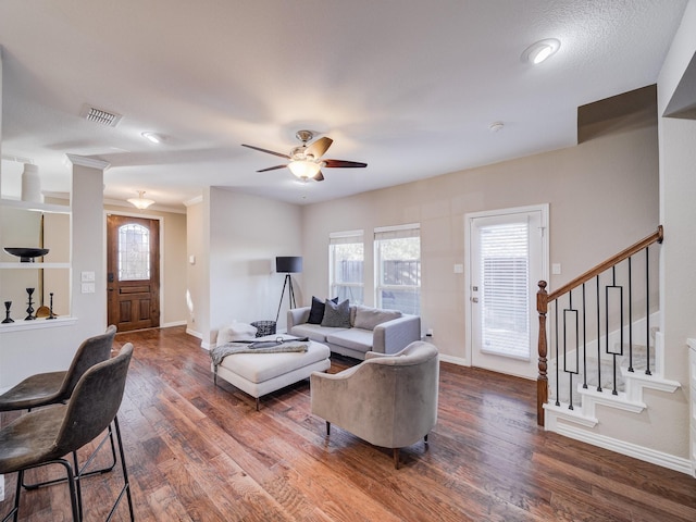 living room with visible vents, plenty of natural light, stairway, and wood finished floors