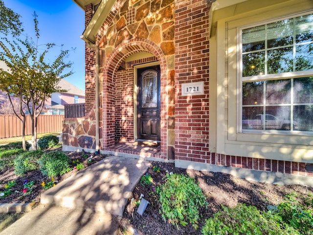 entrance to property featuring fence and brick siding