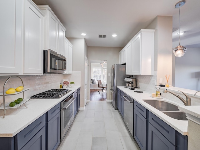 kitchen with a sink, visible vents, white cabinets, appliances with stainless steel finishes, and decorative backsplash