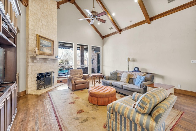 living room featuring high vaulted ceiling, beam ceiling, a fireplace, and wood finished floors