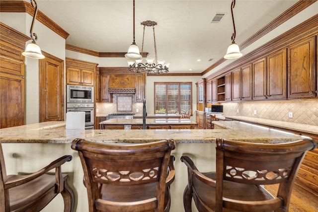 kitchen with a center island with sink, stainless steel appliances, backsplash, ornamental molding, and wood finished floors