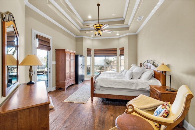 bedroom with dark wood-style floors, a tray ceiling, crown molding, visible vents, and baseboards