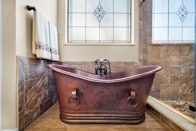 full bath with a freestanding bath and tile walls