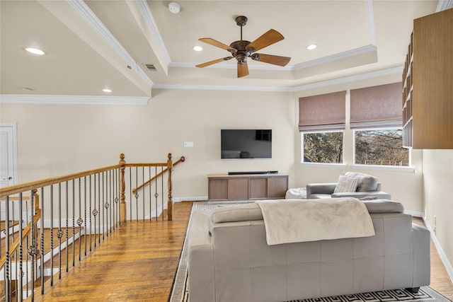 living room with ornamental molding, a raised ceiling, visible vents, and wood finished floors