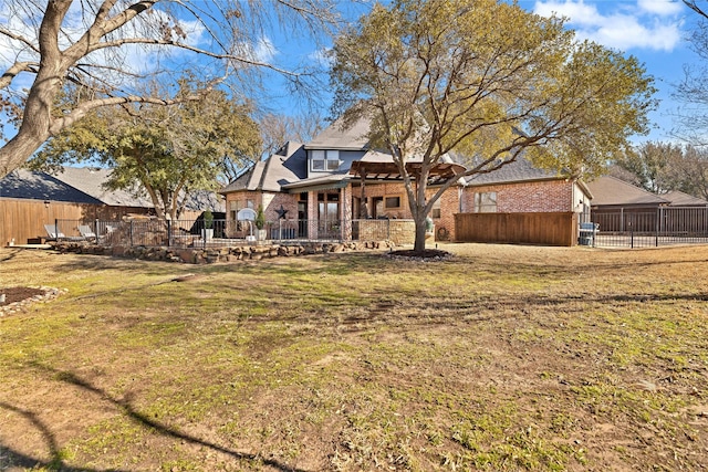 back of property featuring brick siding, a lawn, and fence