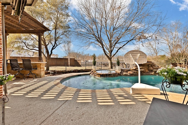 view of pool featuring a patio, outdoor dry bar, a pool with connected hot tub, a pergola, and a fenced backyard