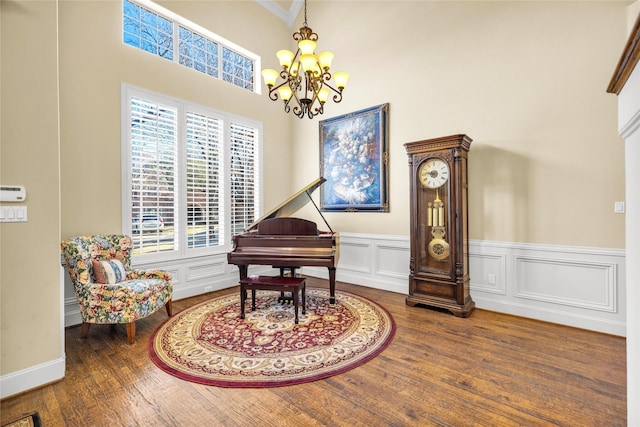 living area featuring a wainscoted wall, a decorative wall, wood finished floors, and a notable chandelier