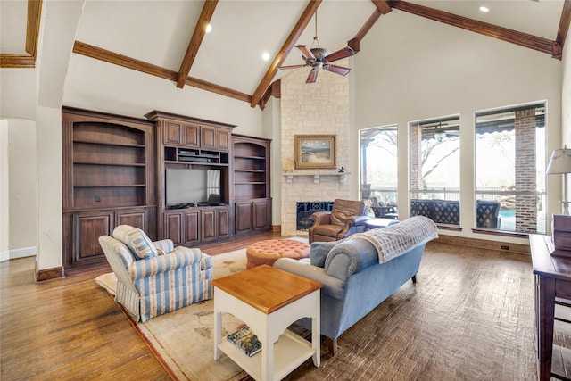 living area with a large fireplace, ceiling fan, wood finished floors, beamed ceiling, and high vaulted ceiling