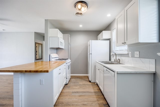 kitchen featuring butcher block counters, white cabinetry, a sink, light wood-type flooring, and white appliances