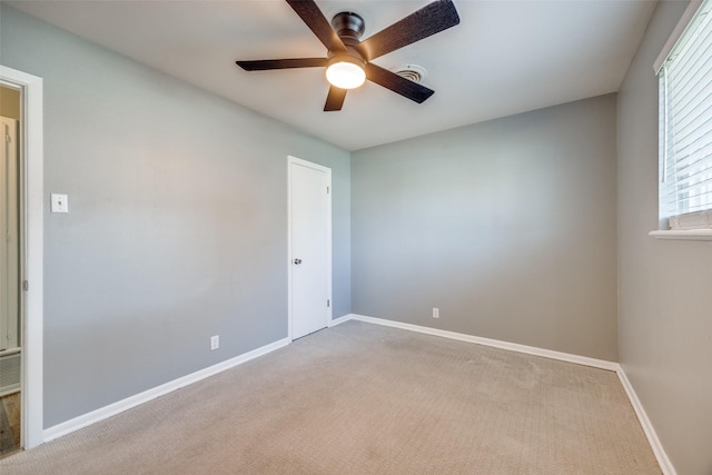 carpeted empty room featuring ceiling fan and baseboards