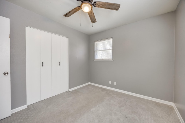 unfurnished bedroom featuring light carpet, a closet, a ceiling fan, and baseboards