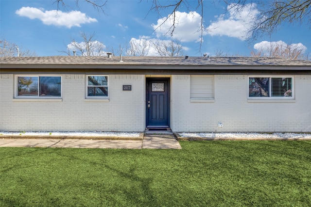 rear view of house with brick siding and a yard