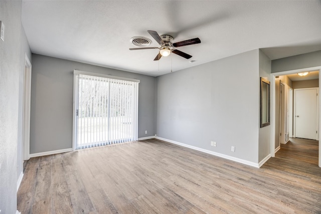 empty room with baseboards, visible vents, ceiling fan, and wood finished floors