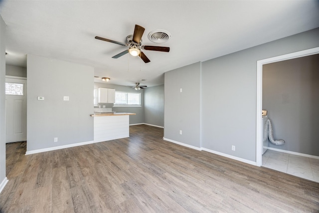 unfurnished living room featuring wood finished floors, visible vents, and baseboards