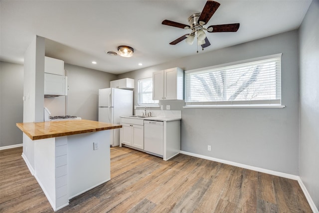 kitchen with white appliances, wood counters, and baseboards