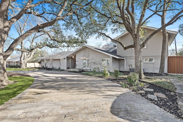 view of front facade featuring central AC, fence, and concrete driveway