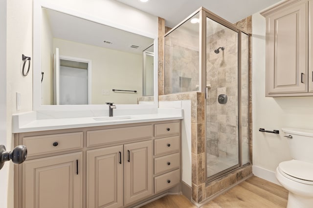 bathroom featuring a stall shower, visible vents, toilet, wood finished floors, and vanity