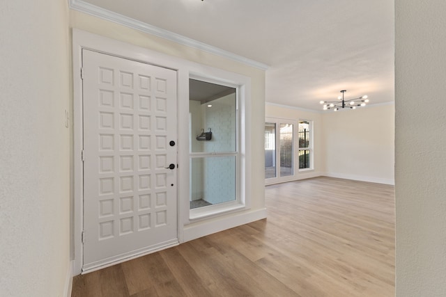 entrance foyer with an inviting chandelier, baseboards, crown molding, and wood finished floors