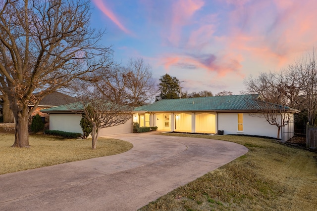 single story home with curved driveway, a tiled roof, an attached garage, a front lawn, and stucco siding