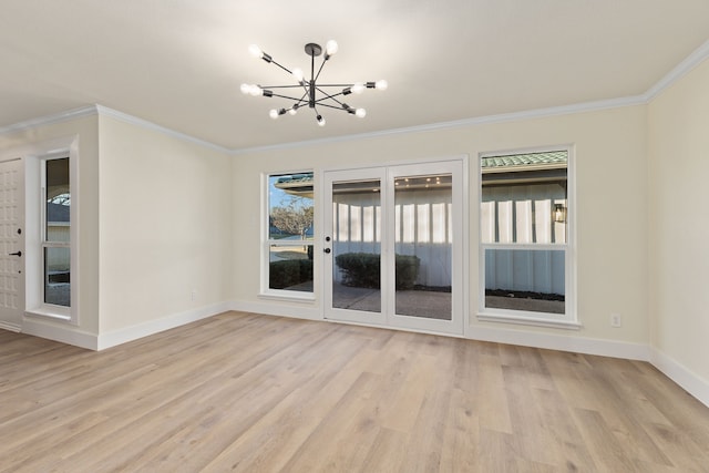 spare room with light wood finished floors, baseboards, ornamental molding, and a notable chandelier