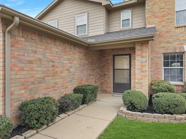 property entrance with brick siding and roof with shingles