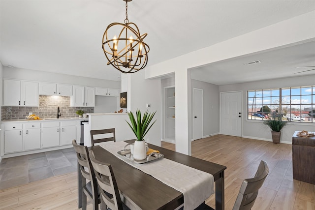 dining area with light wood finished floors, an inviting chandelier, visible vents, and baseboards