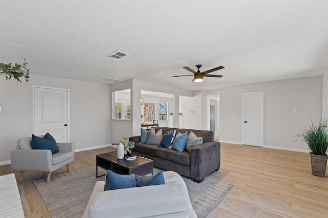 living area with visible vents, ceiling fan, light wood-style flooring, and baseboards