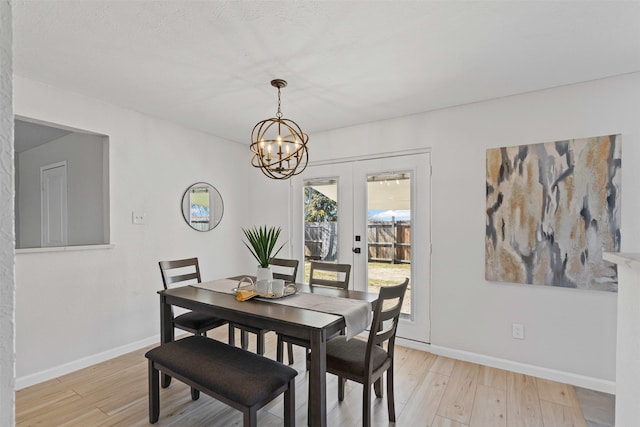 dining area featuring light wood-style floors, baseboards, and an inviting chandelier