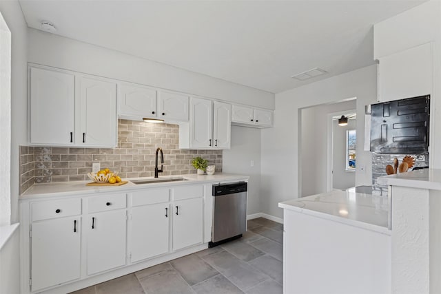 kitchen with decorative backsplash, white cabinets, dishwasher, and a sink