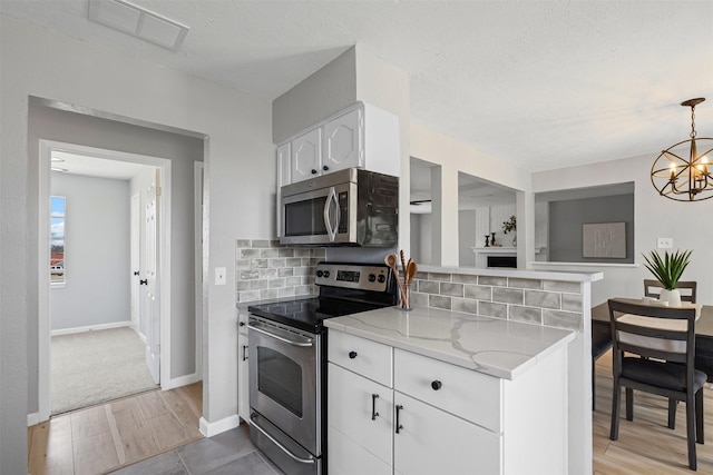 kitchen with tasteful backsplash, visible vents, appliances with stainless steel finishes, an inviting chandelier, and white cabinetry