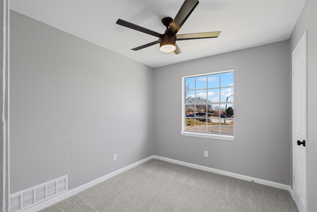 carpeted empty room with a ceiling fan, visible vents, and baseboards