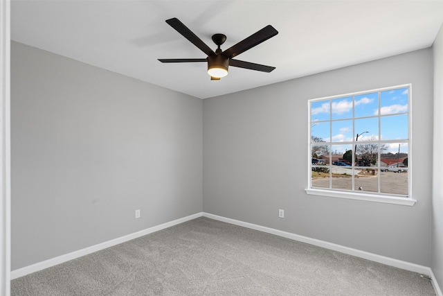 empty room with carpet flooring, a ceiling fan, and baseboards