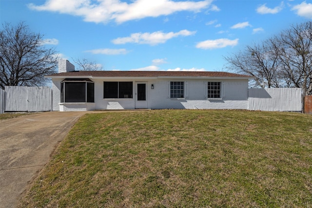 view of front of house with brick siding, a chimney, fence, and a front yard