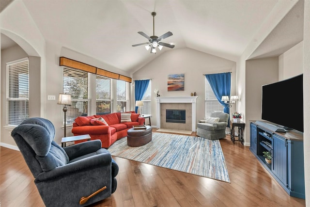 living area featuring vaulted ceiling, a fireplace, light wood-style flooring, and baseboards