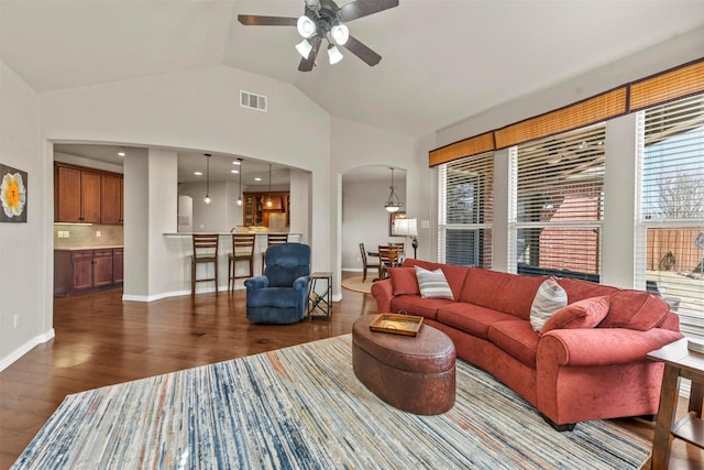 living room featuring dark wood-style floors, arched walkways, lofted ceiling, visible vents, and baseboards