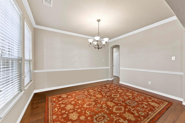 spare room featuring visible vents, arched walkways, wood finished floors, and ornamental molding