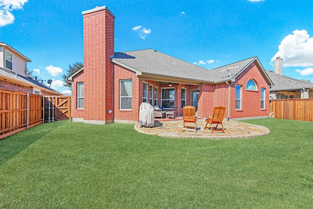 rear view of house with brick siding, a patio, a chimney, a lawn, and a fenced backyard