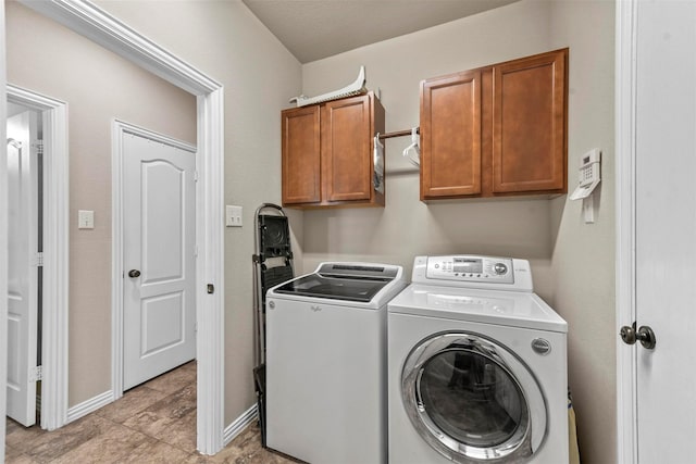 clothes washing area featuring cabinet space, washing machine and dryer, and baseboards