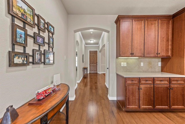 hallway with hardwood / wood-style flooring, baseboards, and arched walkways