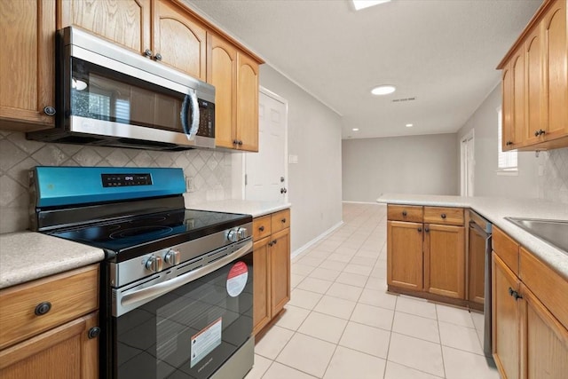 kitchen featuring stainless steel appliances, light tile patterned flooring, and light countertops