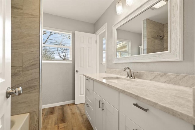 full bath featuring a shower, vanity, wood finished floors, baseboards, and a bath