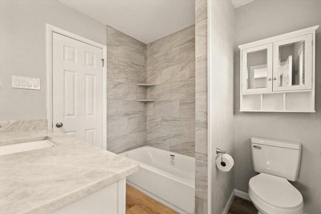 bathroom with bathtub / shower combination, toilet, wood finished floors, vanity, and baseboards