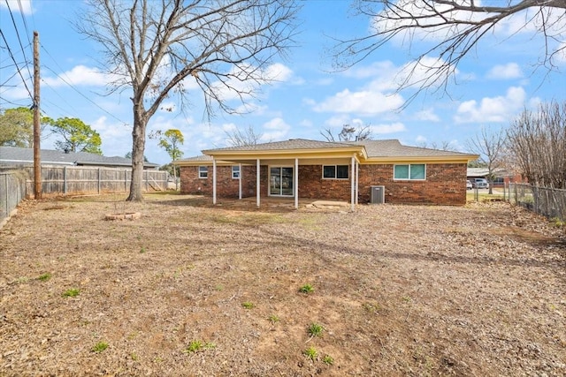 back of house with a fenced backyard, brick siding, and central air condition unit