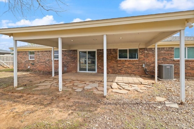 rear view of house with a patio, brick siding, cooling unit, and fence