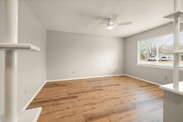 empty room featuring ceiling fan, baseboards, and wood finished floors