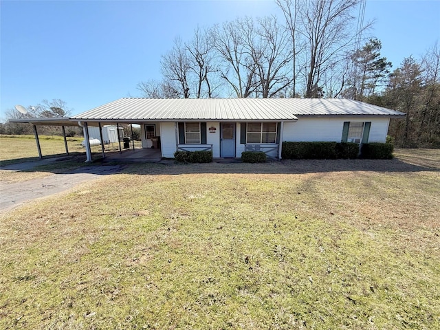 single story home featuring metal roof, an attached carport, a front yard, and driveway