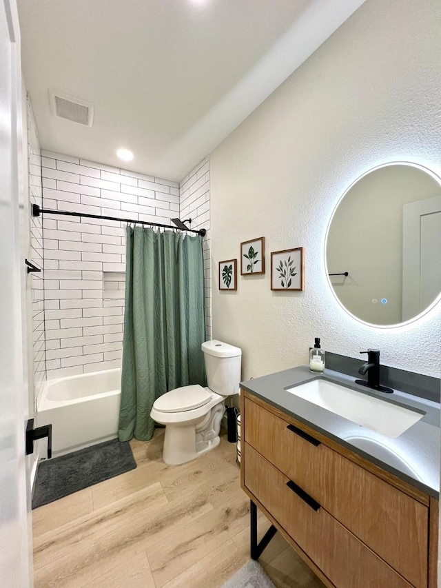 bathroom with visible vents, toilet, wood finished floors, shower / bath combo with shower curtain, and vanity