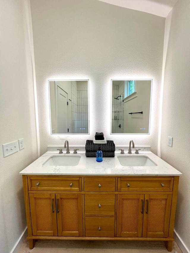 bathroom featuring double vanity, walk in shower, and a sink