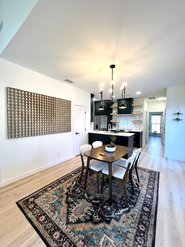 dining area featuring light wood-type flooring, visible vents, and baseboards