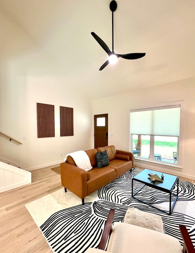 living room featuring a ceiling fan, vaulted ceiling, baseboards, and wood finished floors